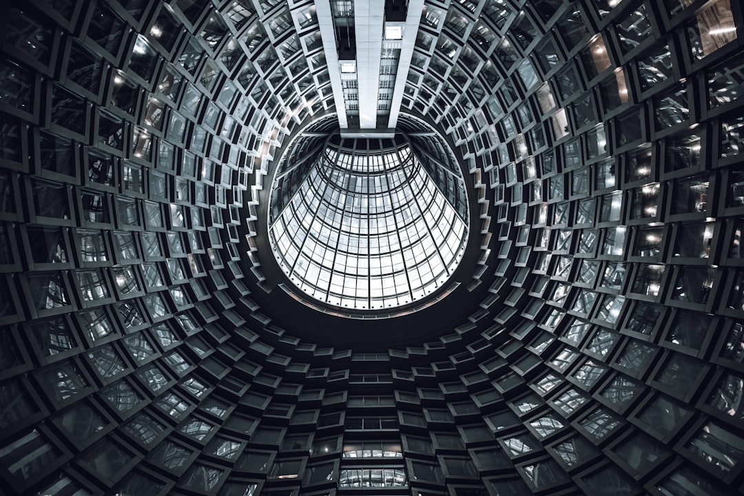 A circular atrium with repeating dark windows and a large glass skylight above